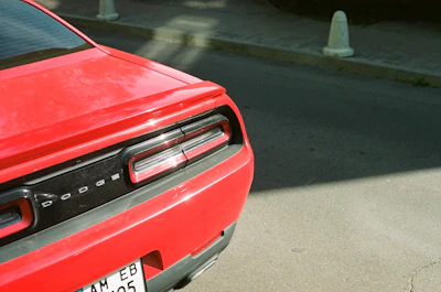 Close-up of a rear diffuser and spoiler on a Dodge Challenger parked on a gritty street.