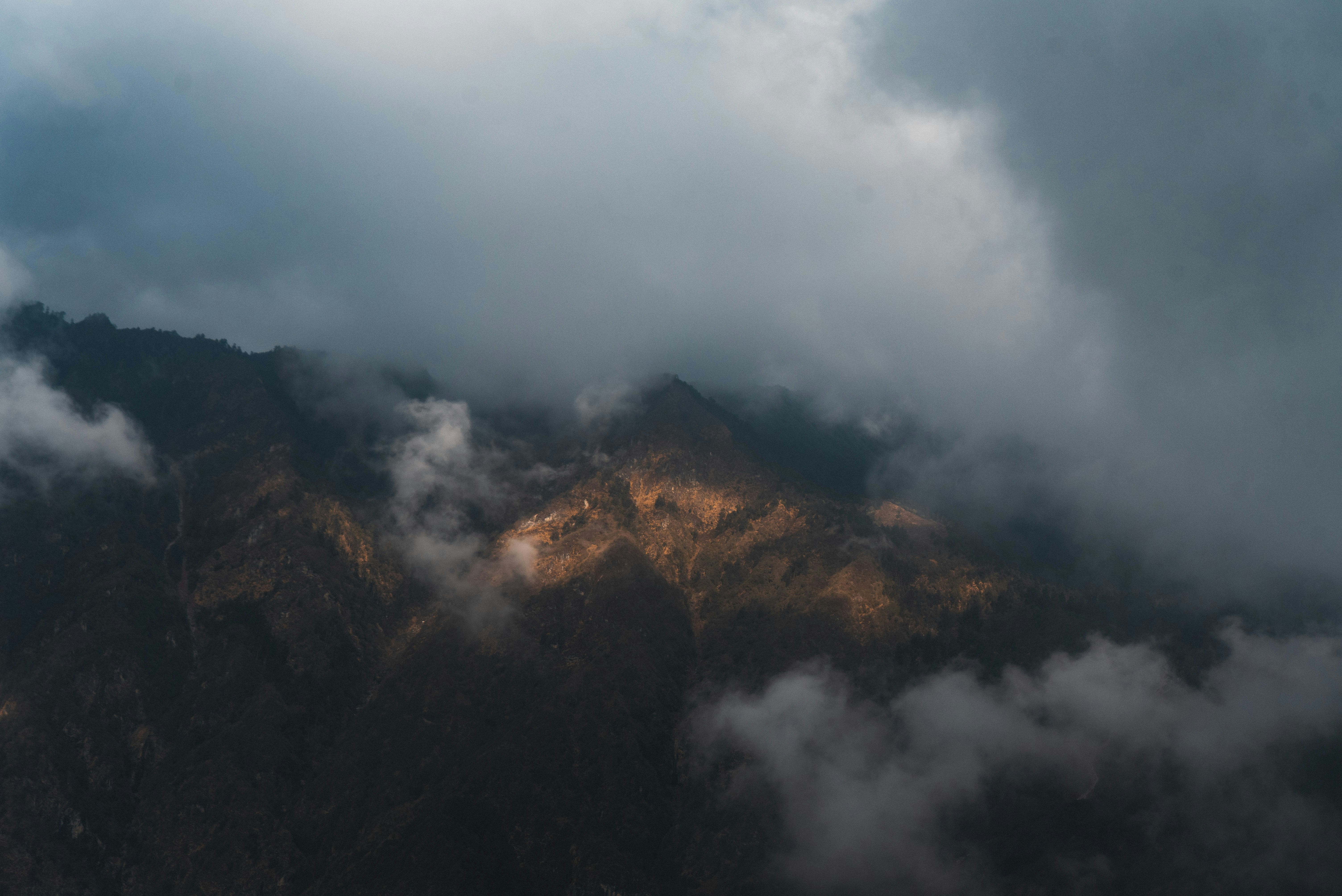 a view of the top of a mountain covered in clouds