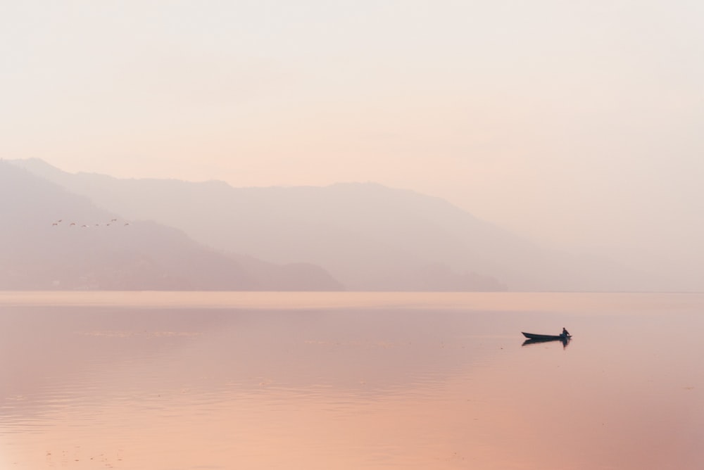 a lone boat floating in the middle of a lake