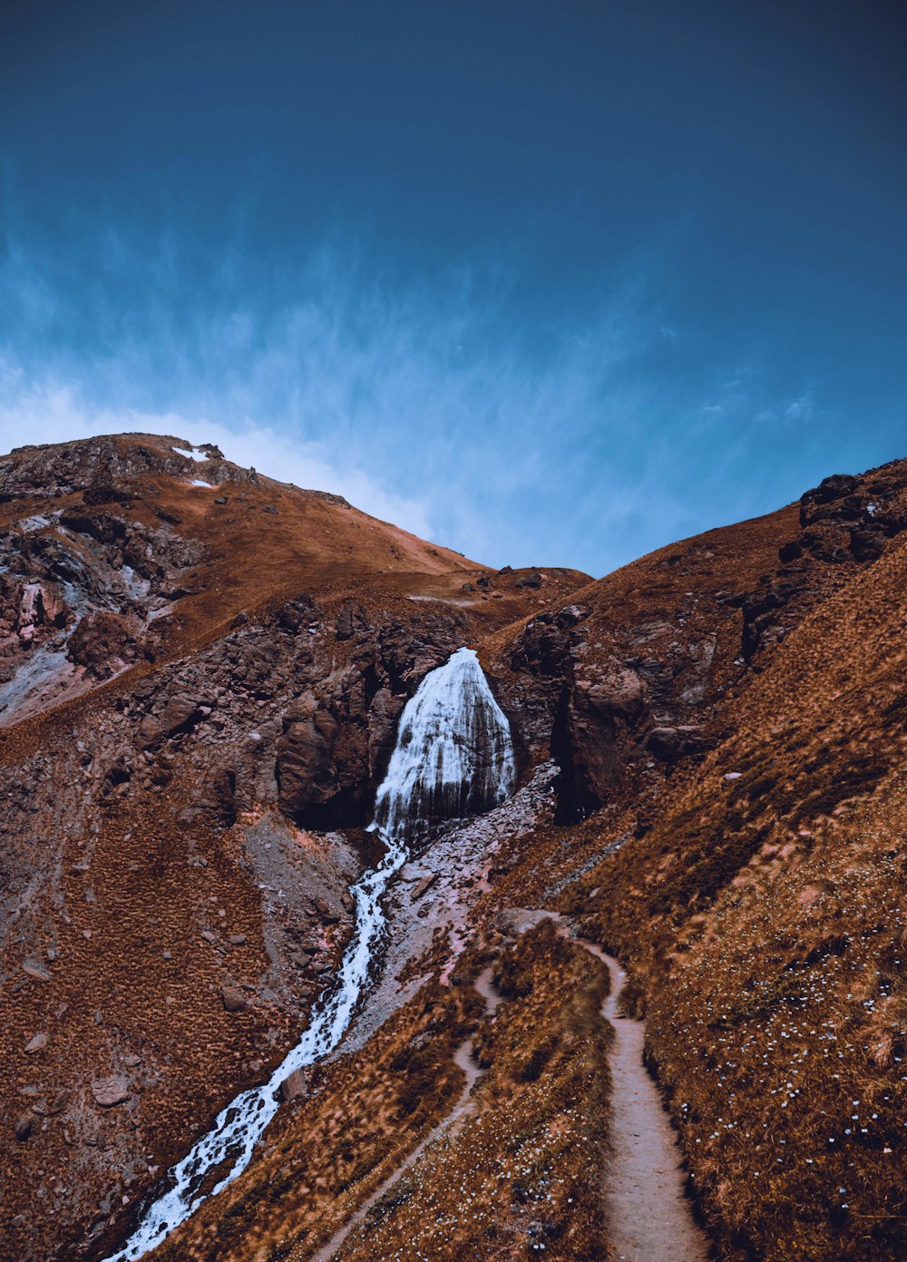 a snow covered mountain with a trail going through it