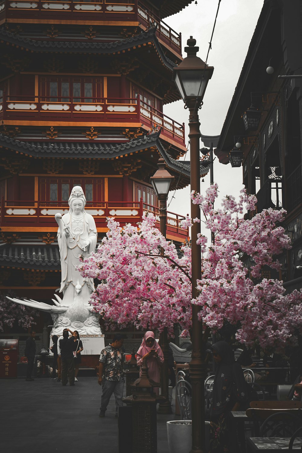 a large white statue sitting next to a pink tree