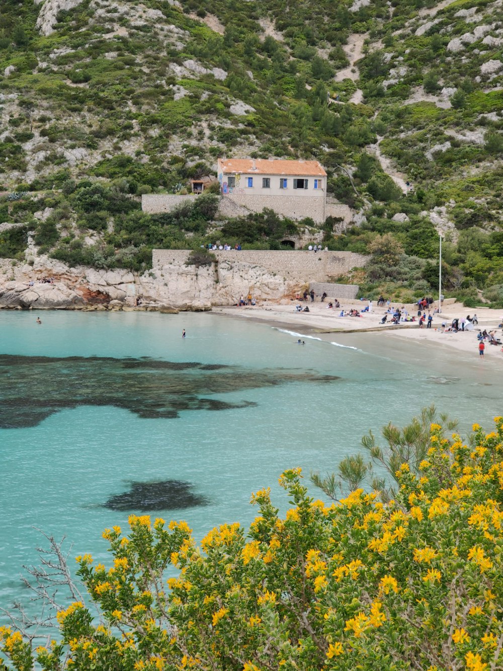 a beach with people on it next to a mountain