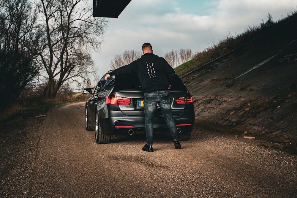 a man sitting on the back of a black car