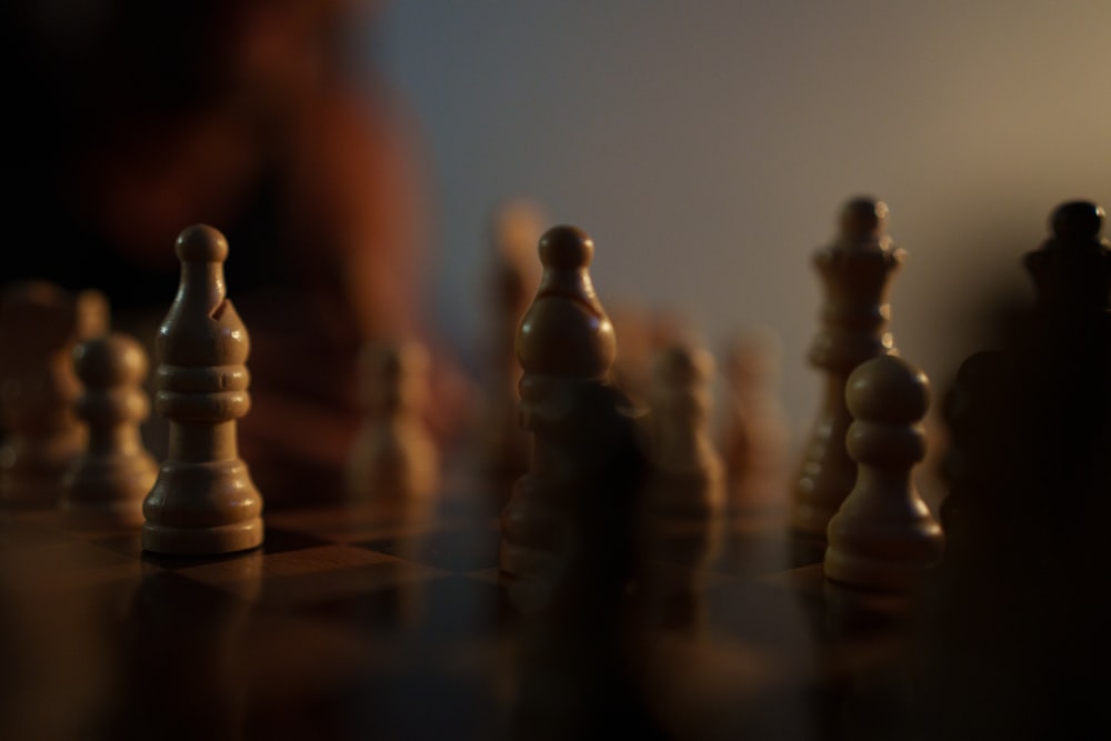 um close up de um tabuleiro de xadrez com uma pessoa ao fundo