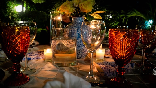 A beautifully set outdoor dining table with elegant floral arrangements and soft lighting at dusk.