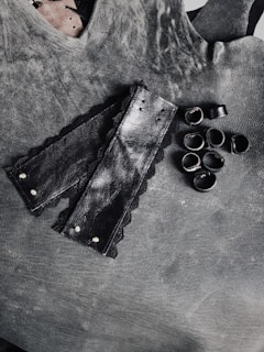 Glossy black leather harness displayed against a moody wine-colored backdrop.