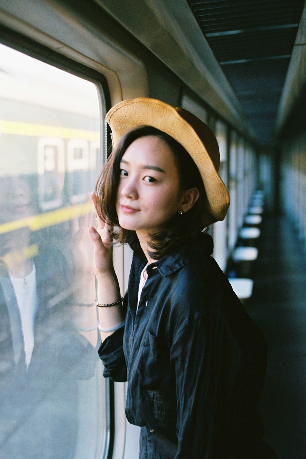 a woman wearing a hat standing next to a window