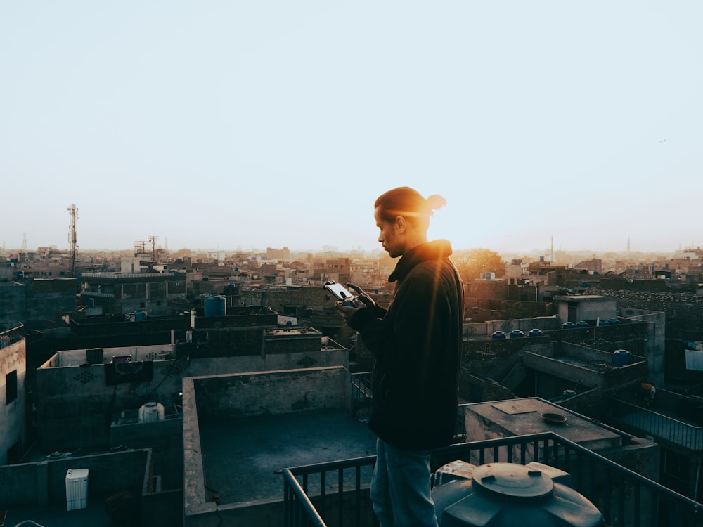 a man standing on top of a roof looking at his cell phone