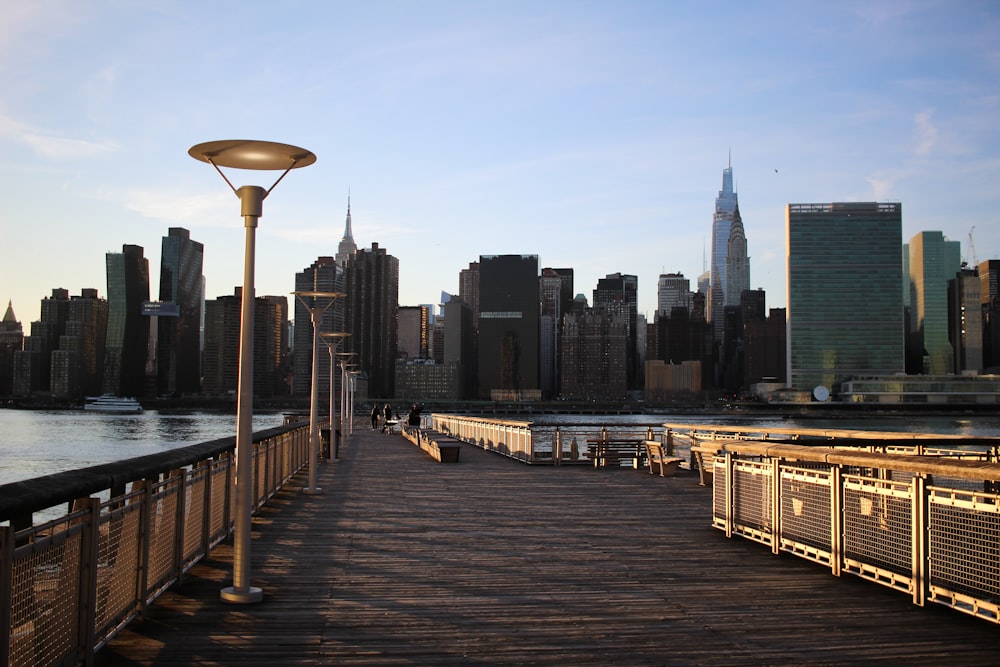 a pier with a lamp post and a city in the background