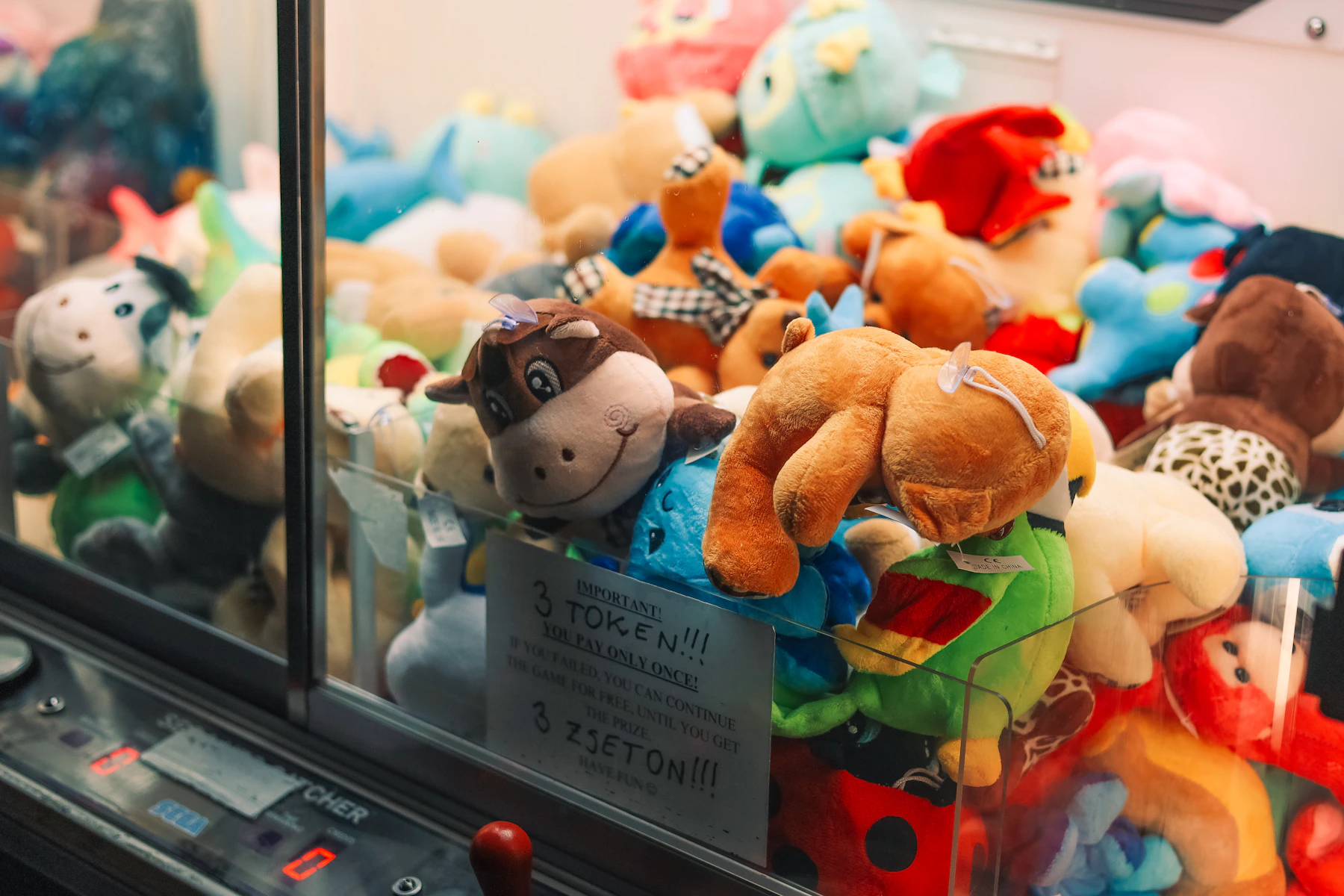 Plush toys of many colors piled behind the glass of an arcade prize machine