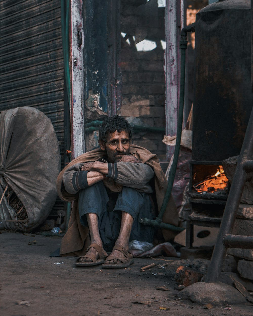 a man sitting on the ground next to a fire place