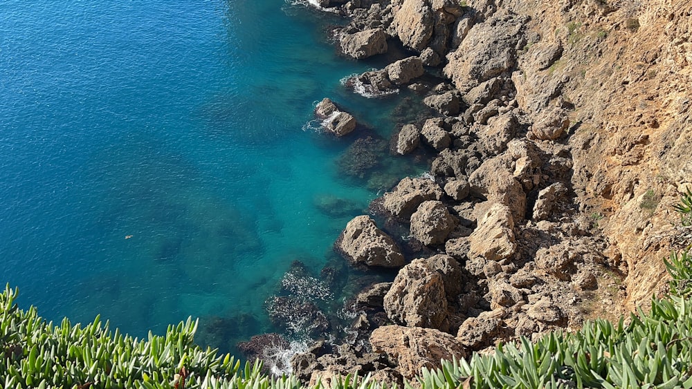 a body of water next to a rocky cliff