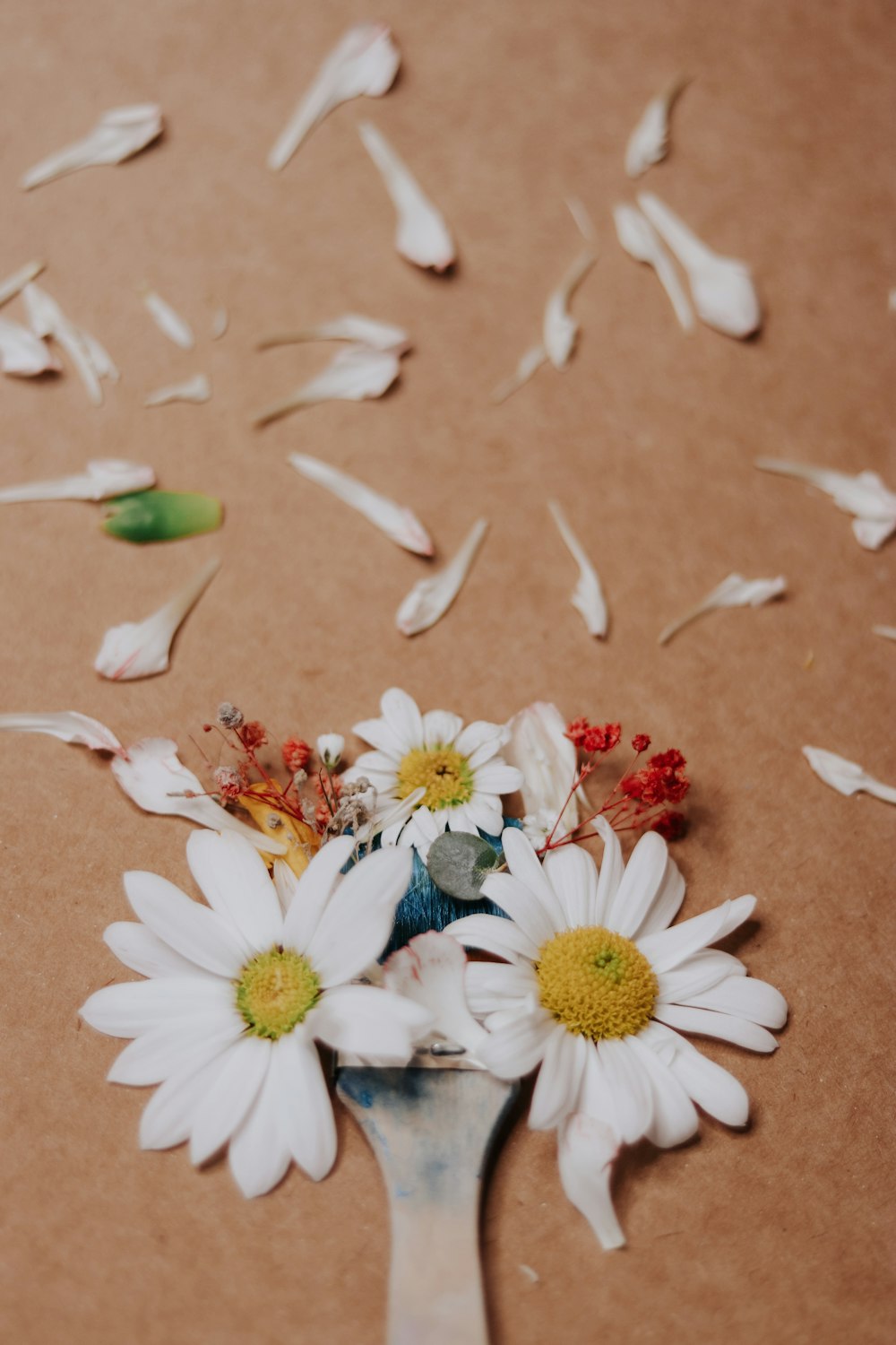 a spoon filled with flowers on top of a table