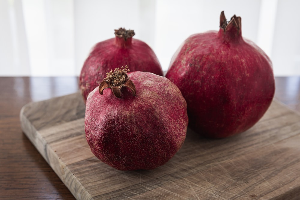 a couple of pomegranates sitting on a cutting board