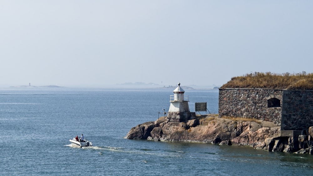 a small boat in a body of water near a lighthouse