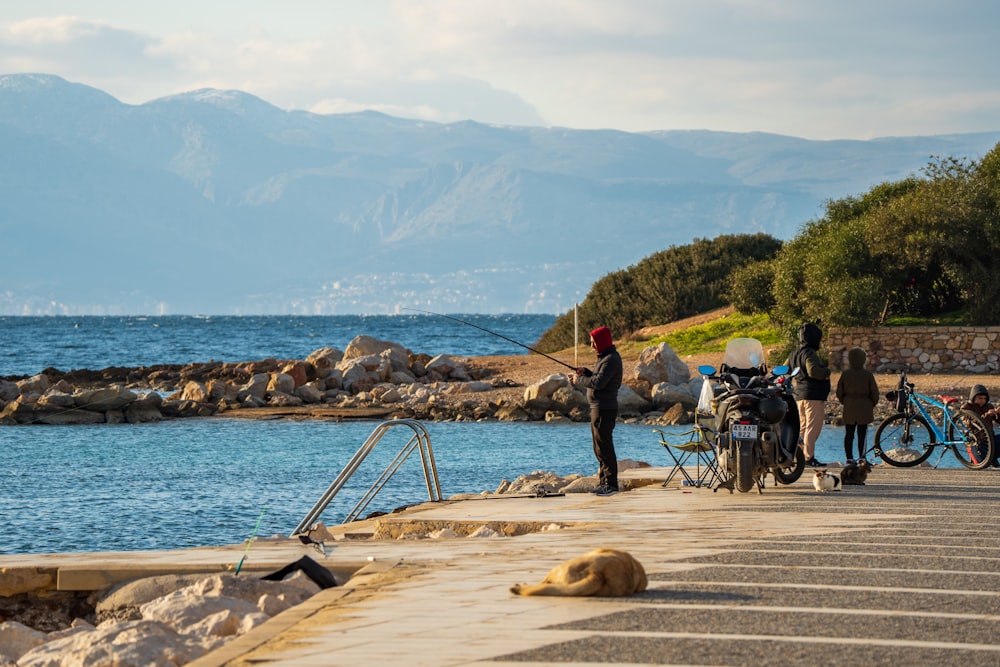 a group of people standing on a pier next to a body of water