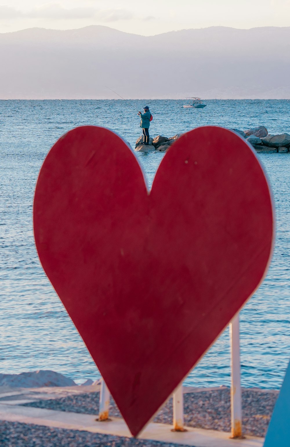 a red heart shaped object in front of a body of water