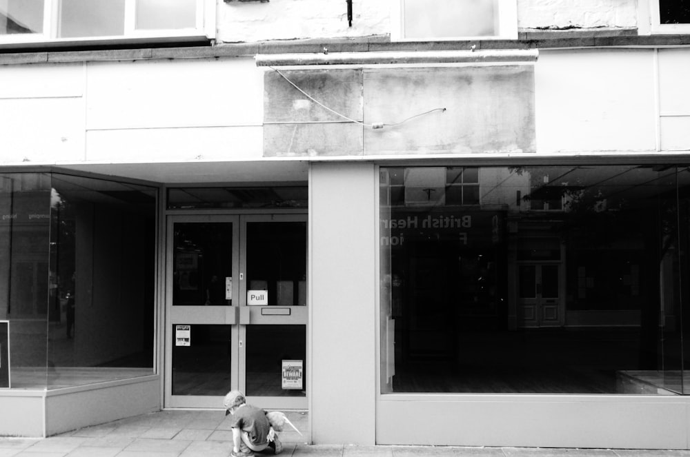 a person sitting on the ground in front of a building