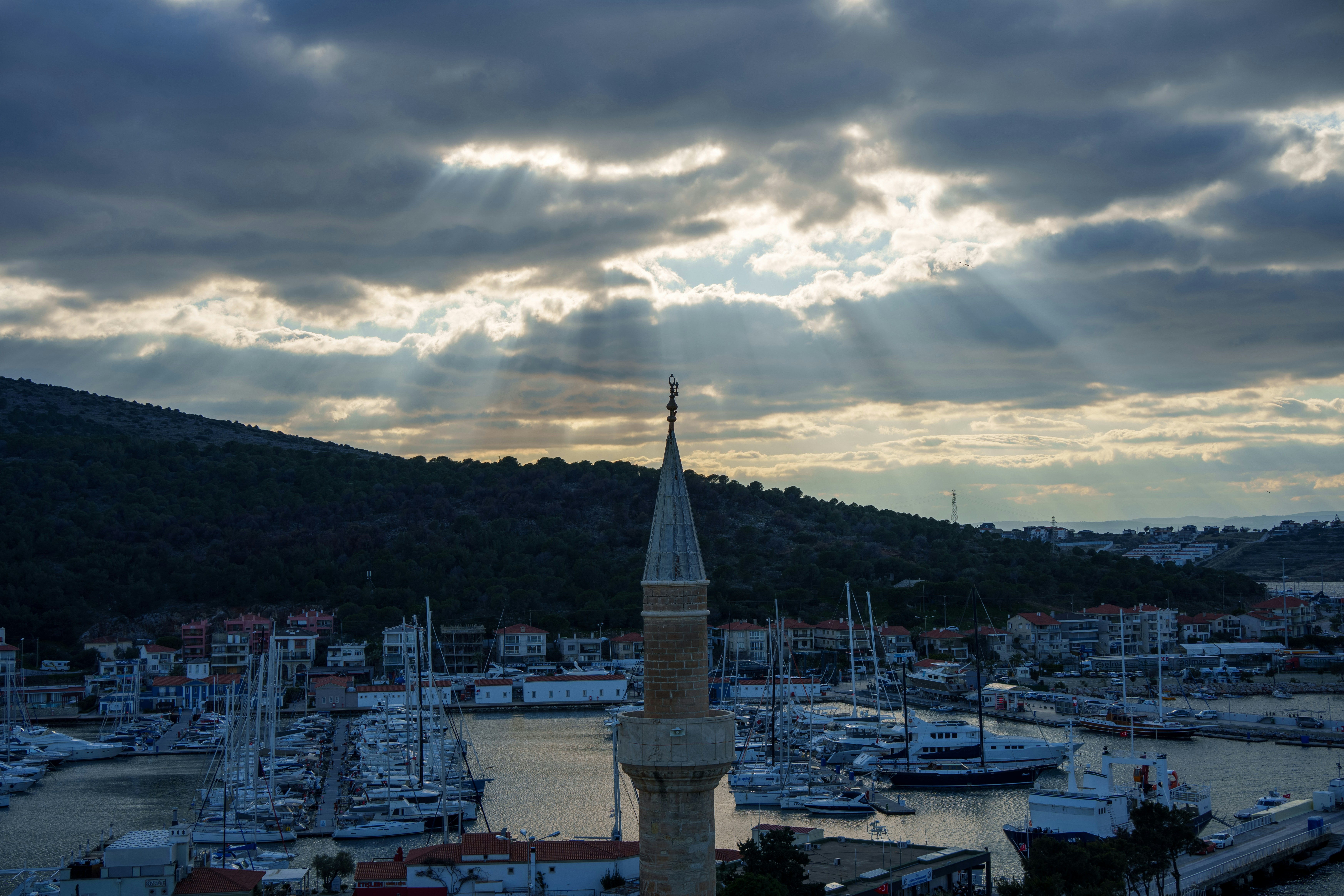 the sun is shining through the clouds over a harbor, 