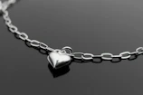 Un collar con un corazón de plata sobre una superficie negra
