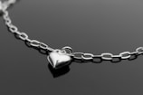 a silver heart necklace on a black surface