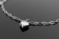Un collar con un corazón de plata sobre una superficie negra