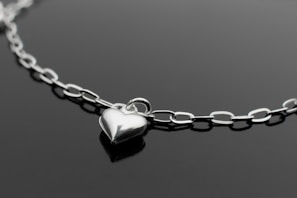 a silver heart necklace on a black surface
