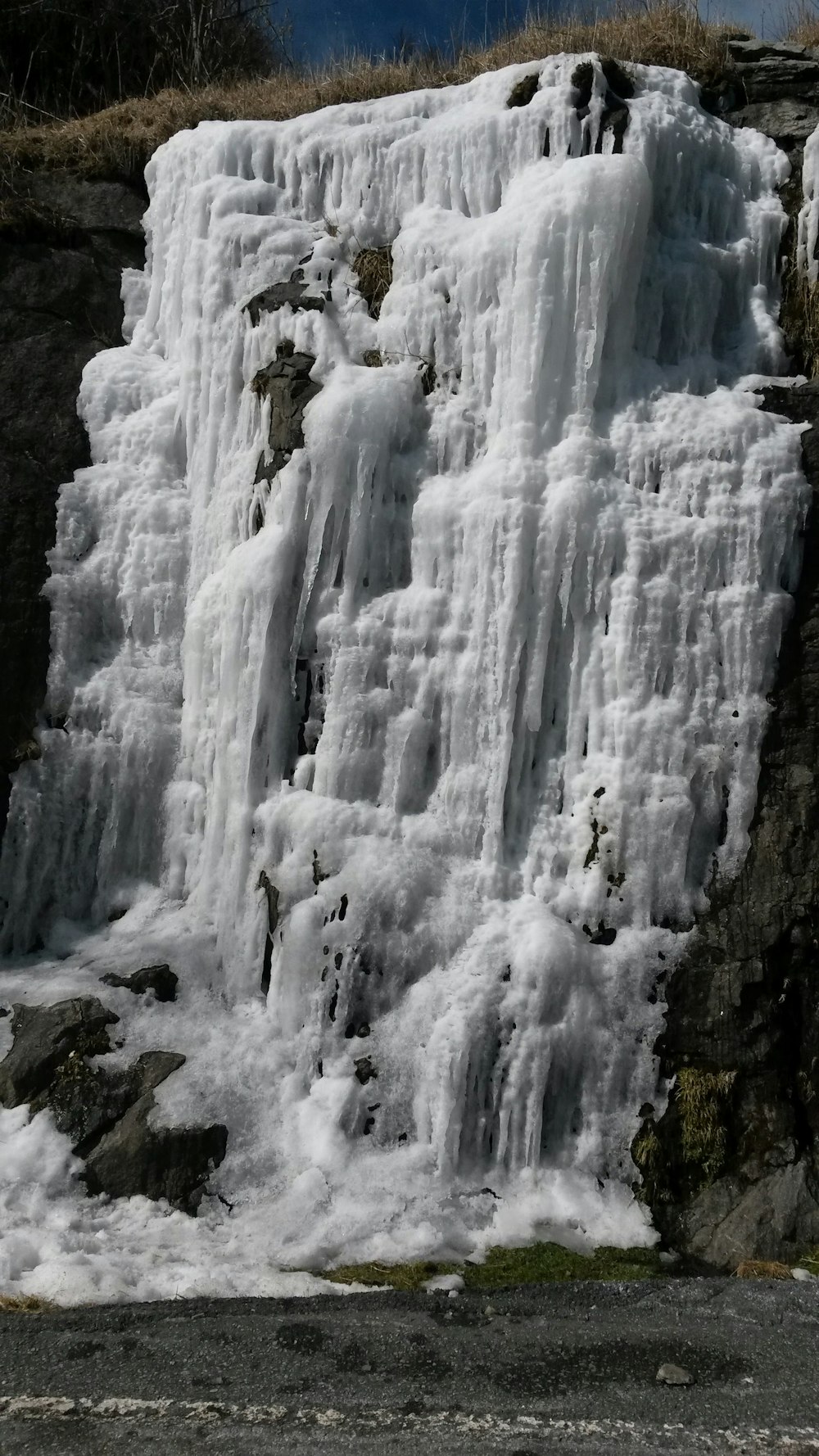a man standing in front of a waterfall covered in ice