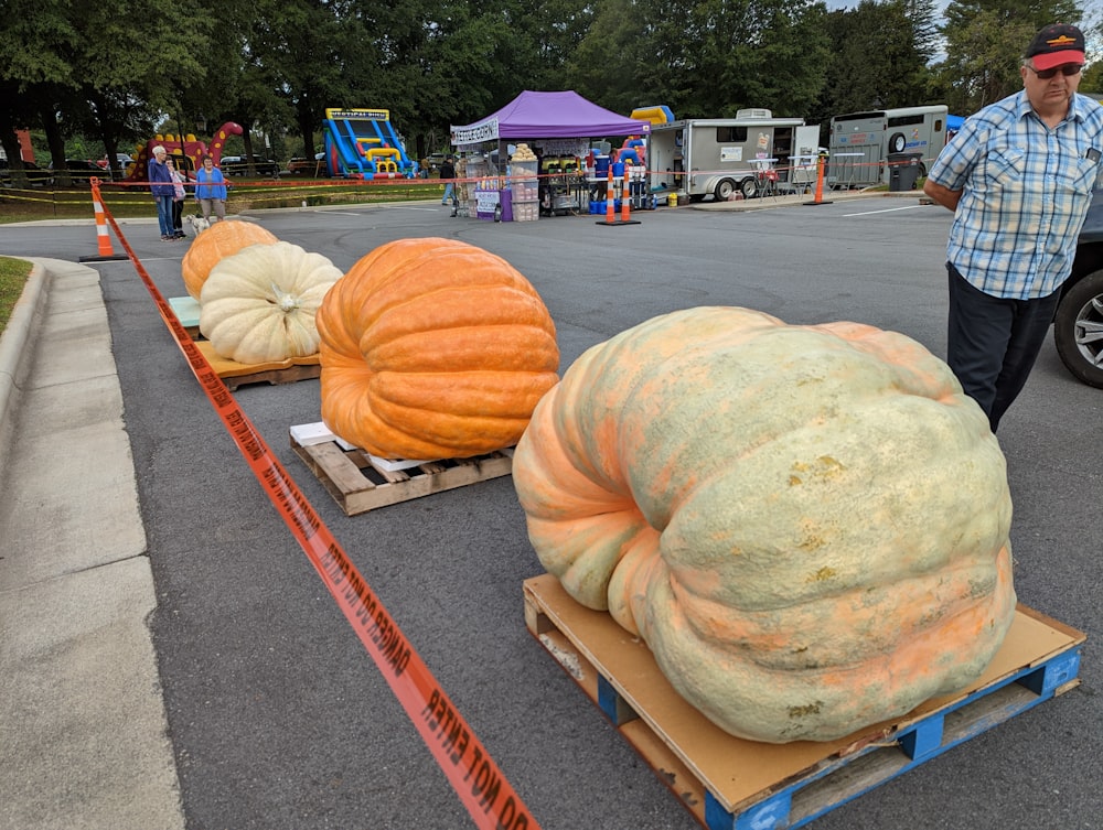 a man standing next to a cart full of pumpkins