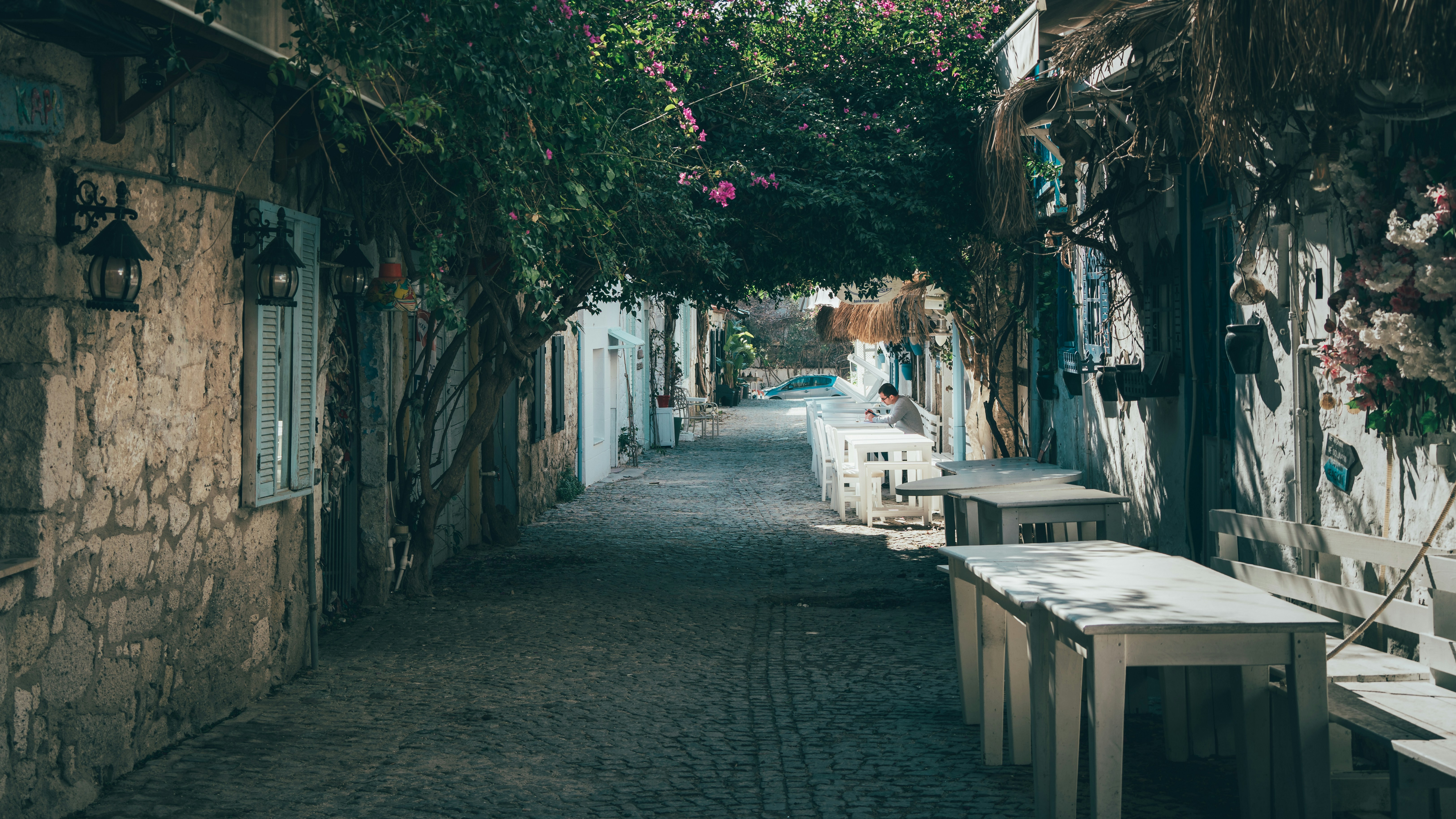a cobblestone street lined with benches and tables, 