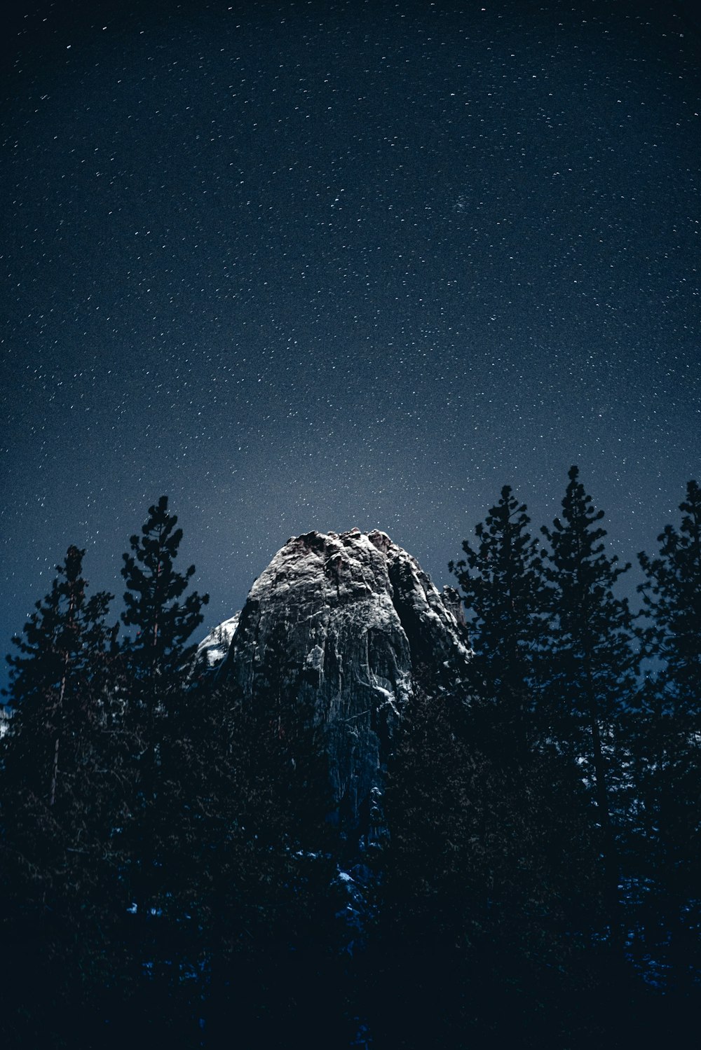 the night sky with stars above a mountain