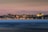 A panoramic view of Istanbul's skyline at dusk, featuring the illuminated silhouettes of historical landmarks against a soft pink and blue sky. The city lights reflect softly on the water in the foreground, adding a sense of calm and beauty.