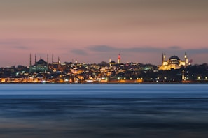 Istanbul skyline at dusk with glowing city lights and Bosphorus bridge.