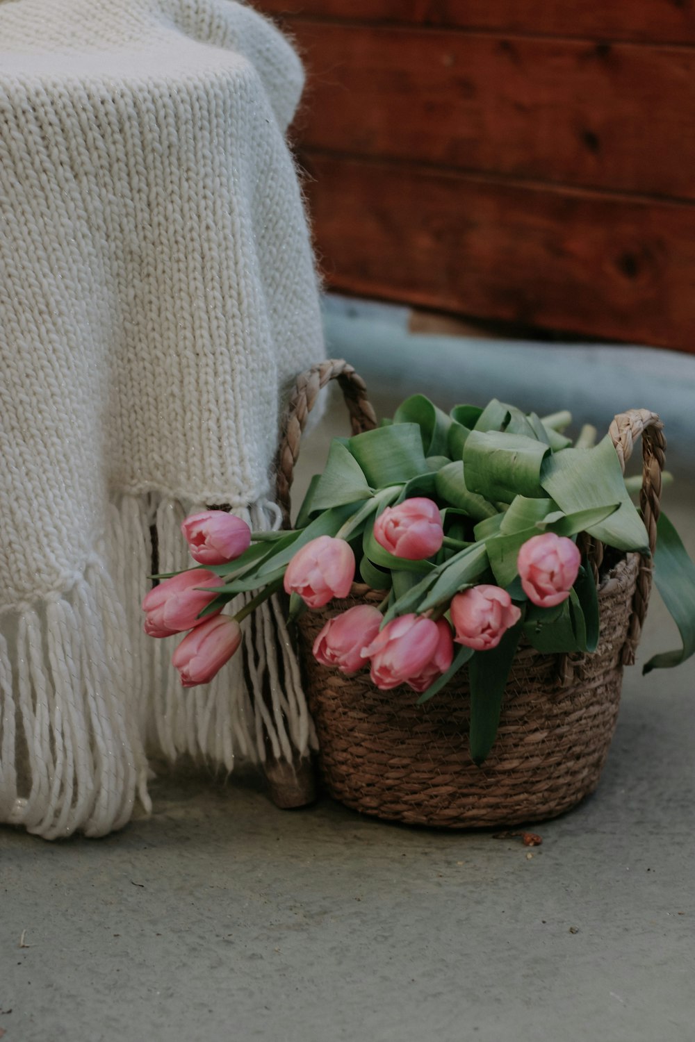 a basket filled with pink flowers next to a blanket