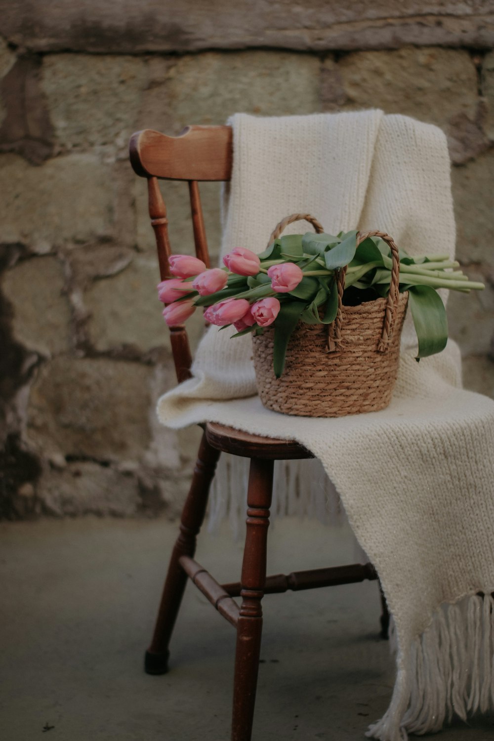 a chair with a blanket and a basket of flowers