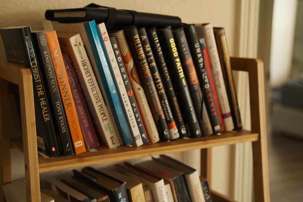 a bookshelf filled with lots of books on top of a hard wood floor