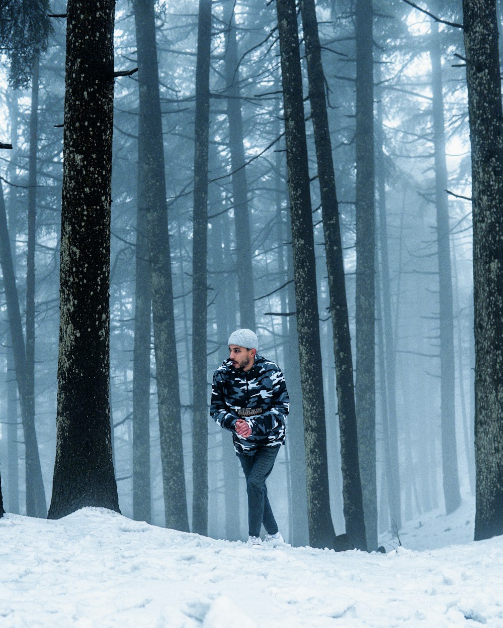 a man standing in the middle of a snowy forest