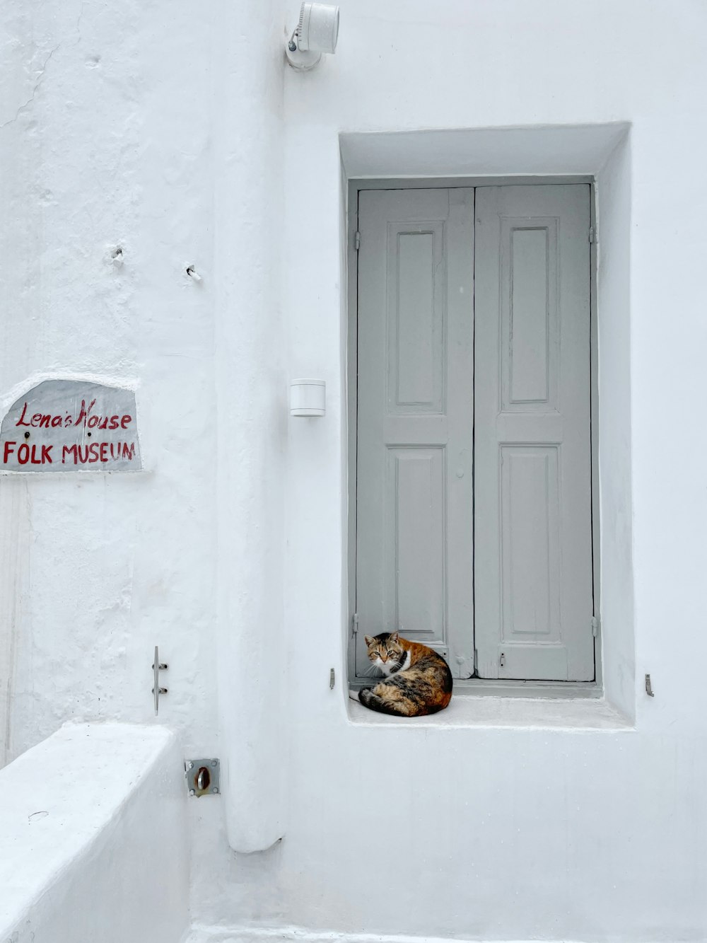 a cat sleeping in a window of a white building
