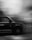 A black and white photo of a moving taxi captured in motion blur, highlighting the dynamic speed. The taxi is partially visible with text on its side, including a logo and social media handle.