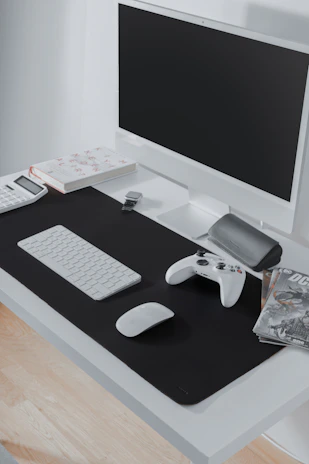 A sleek gaming desk setup featuring a minimalist black mechanical keyboard, dual monitors with subtle blue backlighting, and a clean cable management system.