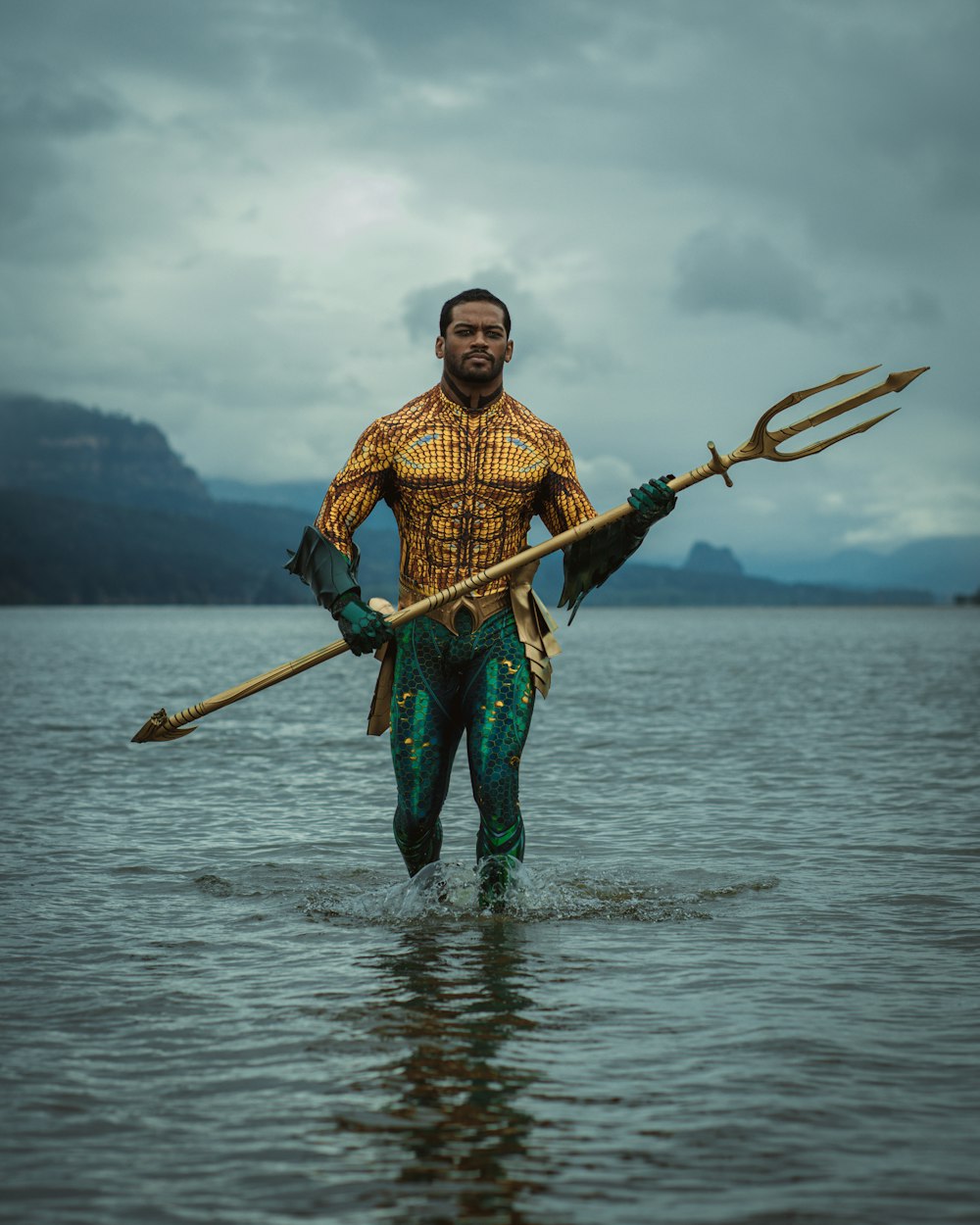 um homem de pé em um corpo de água segurando uma lança