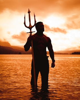 a man is standing in the water with a staff