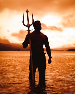 a man is standing in the water with a staff