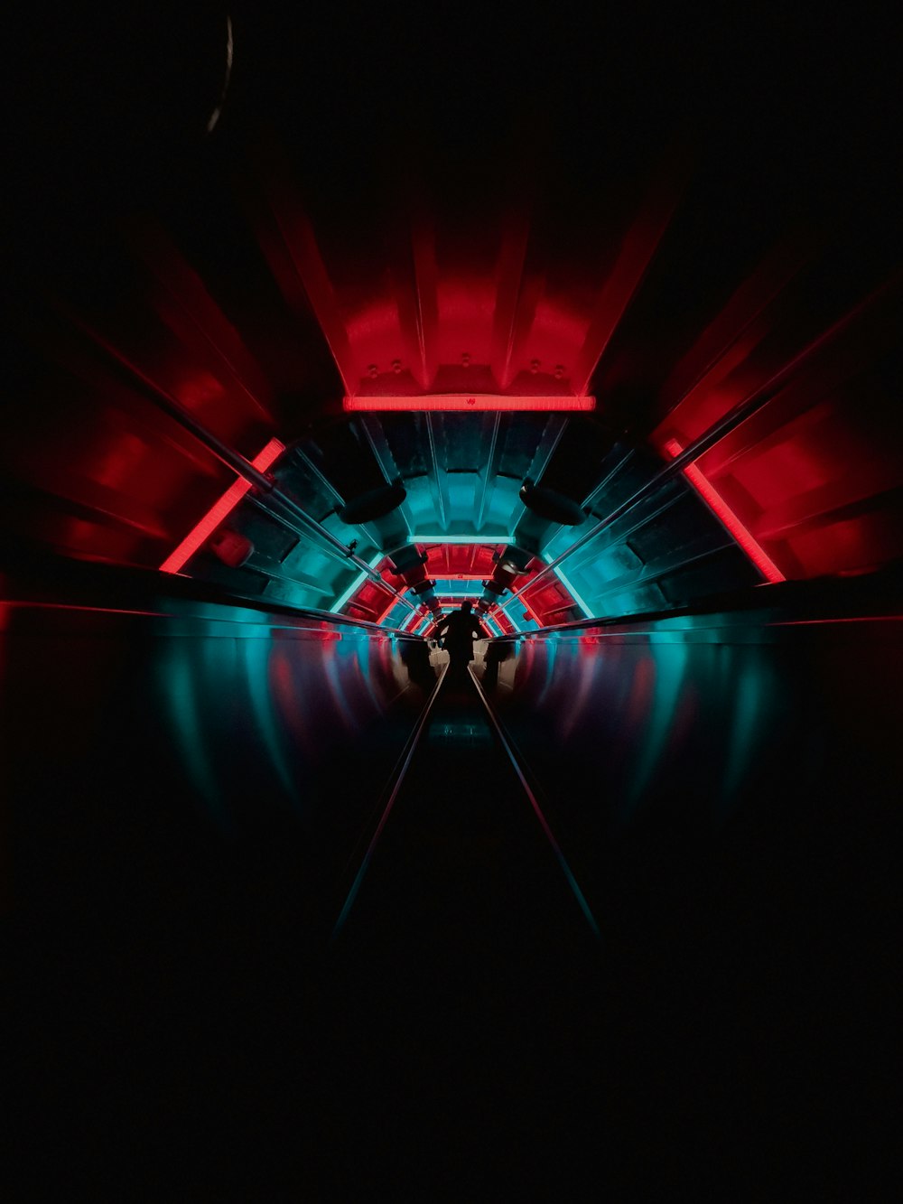 a person standing in a dark tunnel with red and blue lights