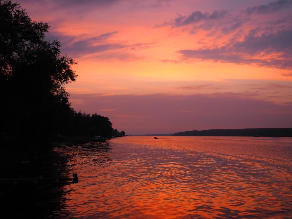 a sunset over a body of water with a boat in the distance