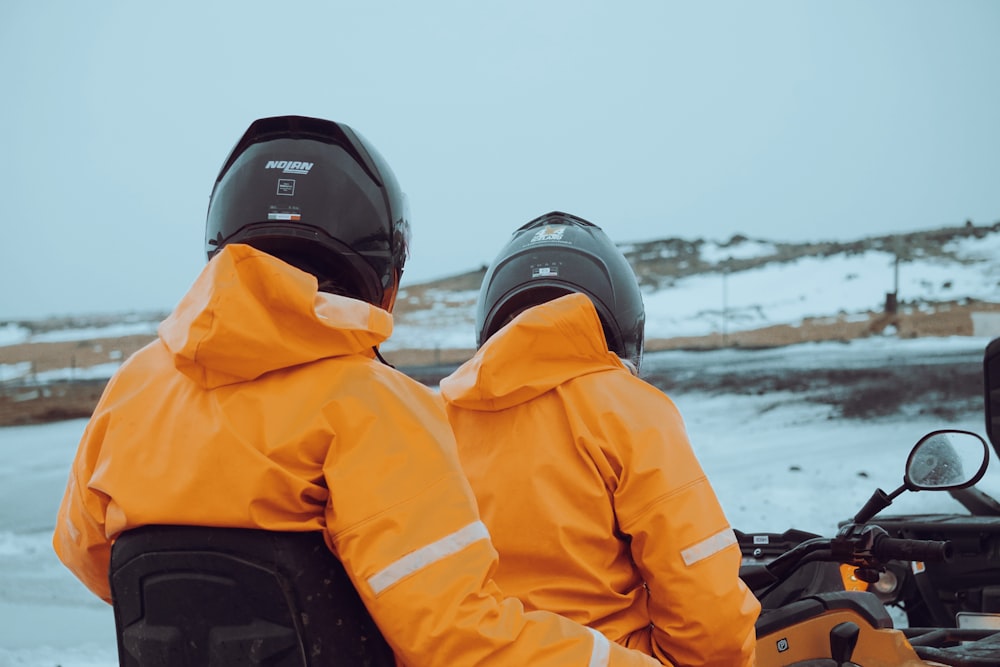 two people sitting on a motorcycle in the snow