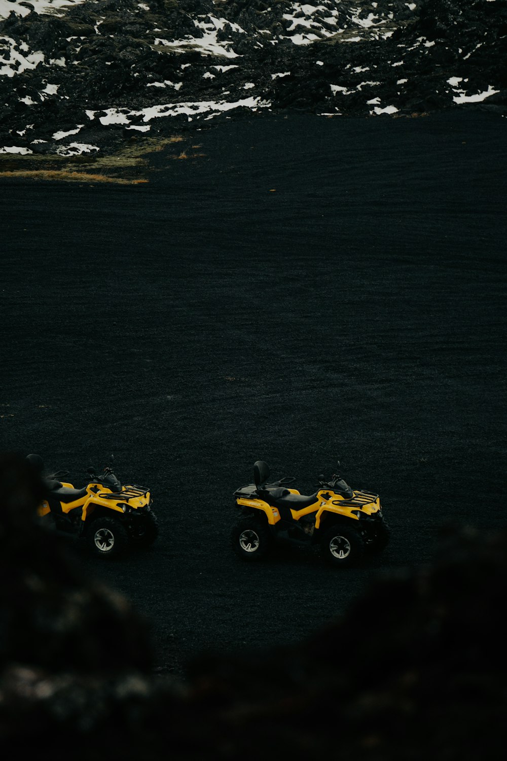 two yellow atvs parked in a black field