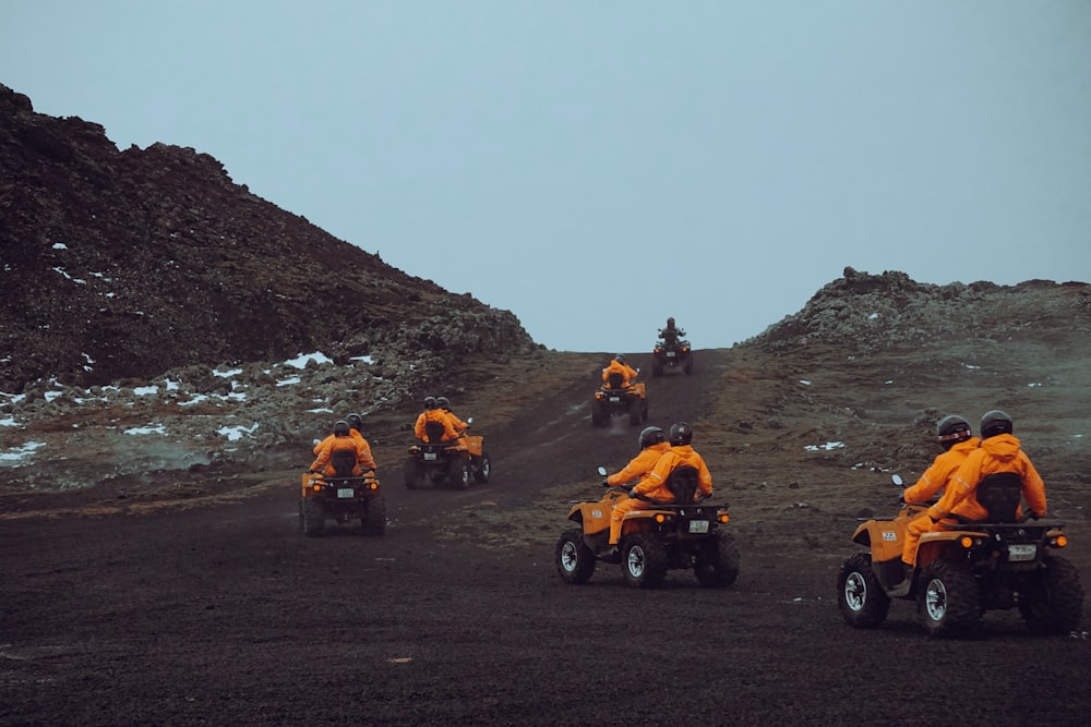 a group of people riding four wheelers down a hill