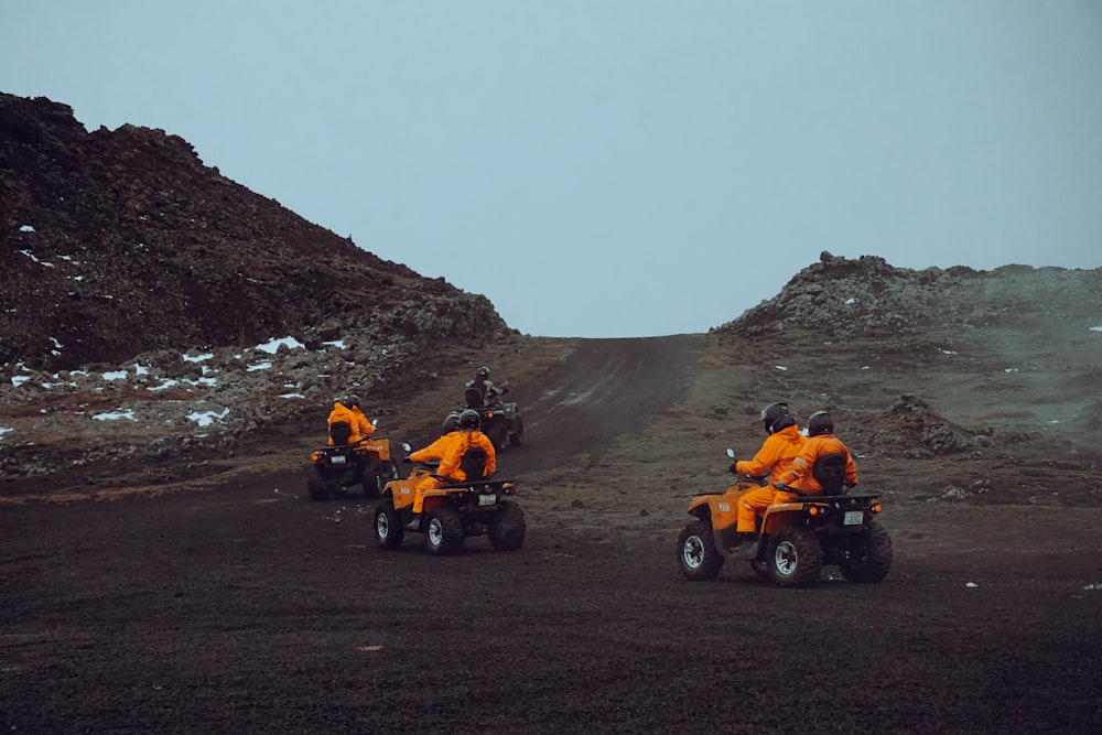 a group of people riding four wheelers on a dirt road