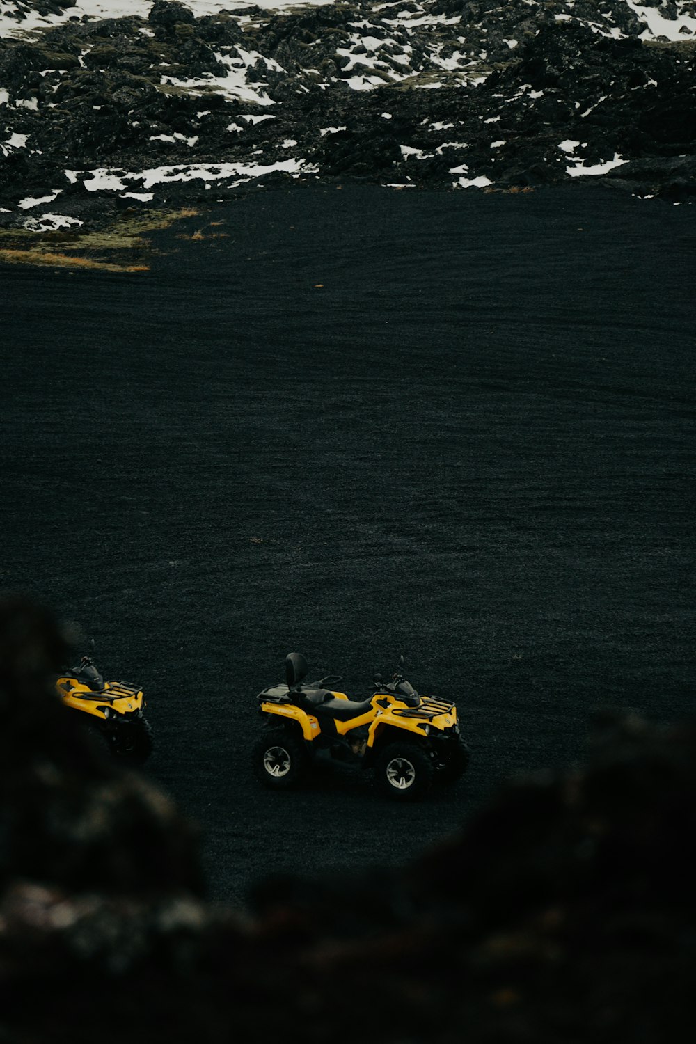 Due ATV gialli sono parcheggiati in un campo nero